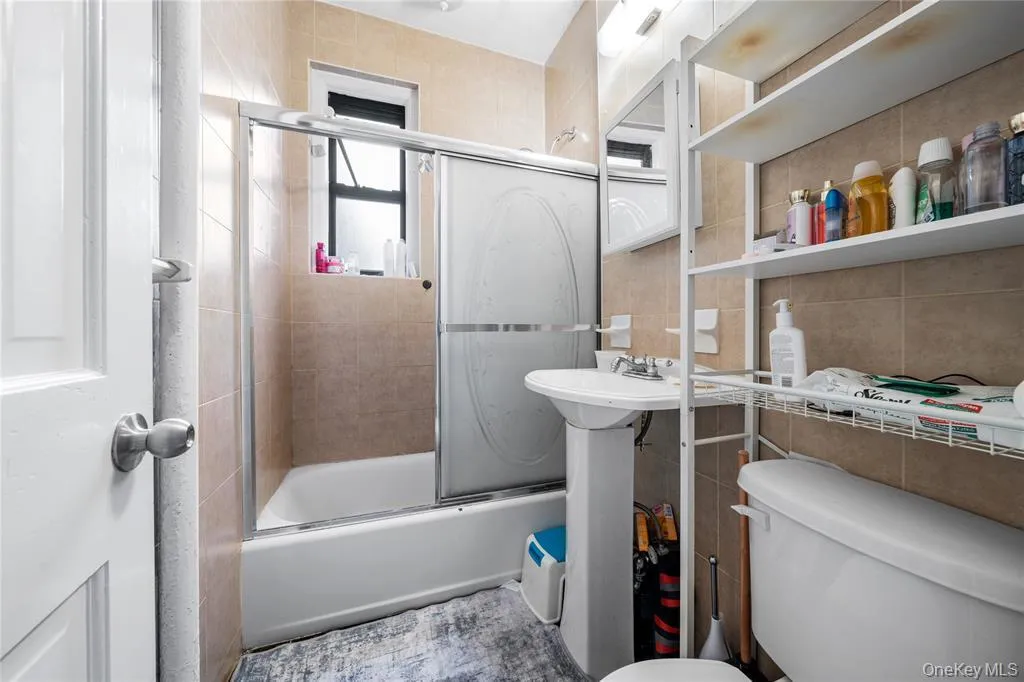 Bathroom featuring enclosed tub / shower combo and tile walls Bathroom featuring enclosed tub / shower combo and tile walls
