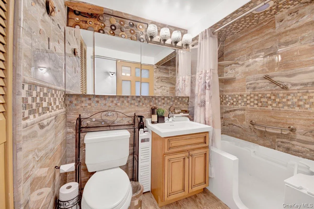 Full bath with shower / bath combination with curtain, tile walls, vanity, and backsplash Full bath with shower / bath combination with curtain, tile walls, vanity, and backsplash
