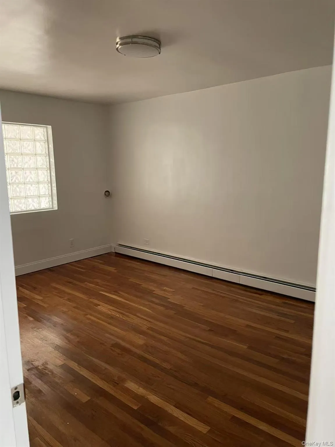 Unfurnished room featuring baseboard heating and dark wood-style floors Unfurnished room featuring baseboard heating and dark wood-style floors