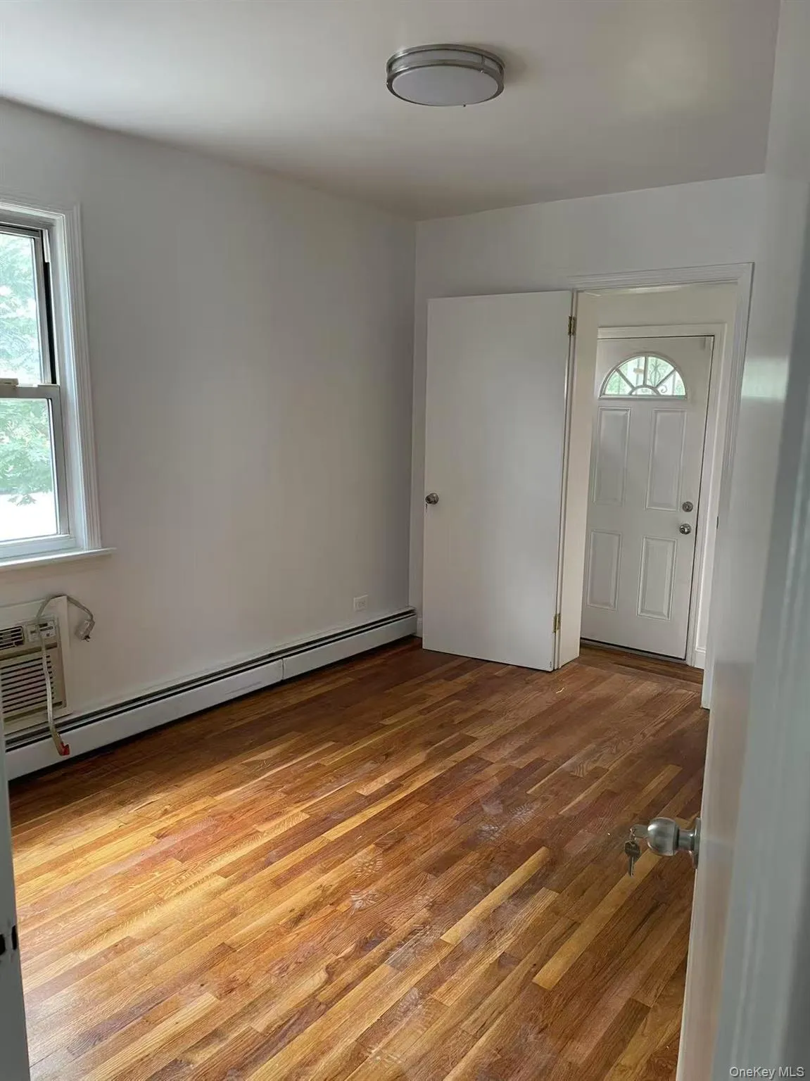 Entrance foyer with light wood finished floors, baseboard heating, and a wall unit AC Entrance foyer with light wood finished floors, baseboard heating, and a wall unit AC