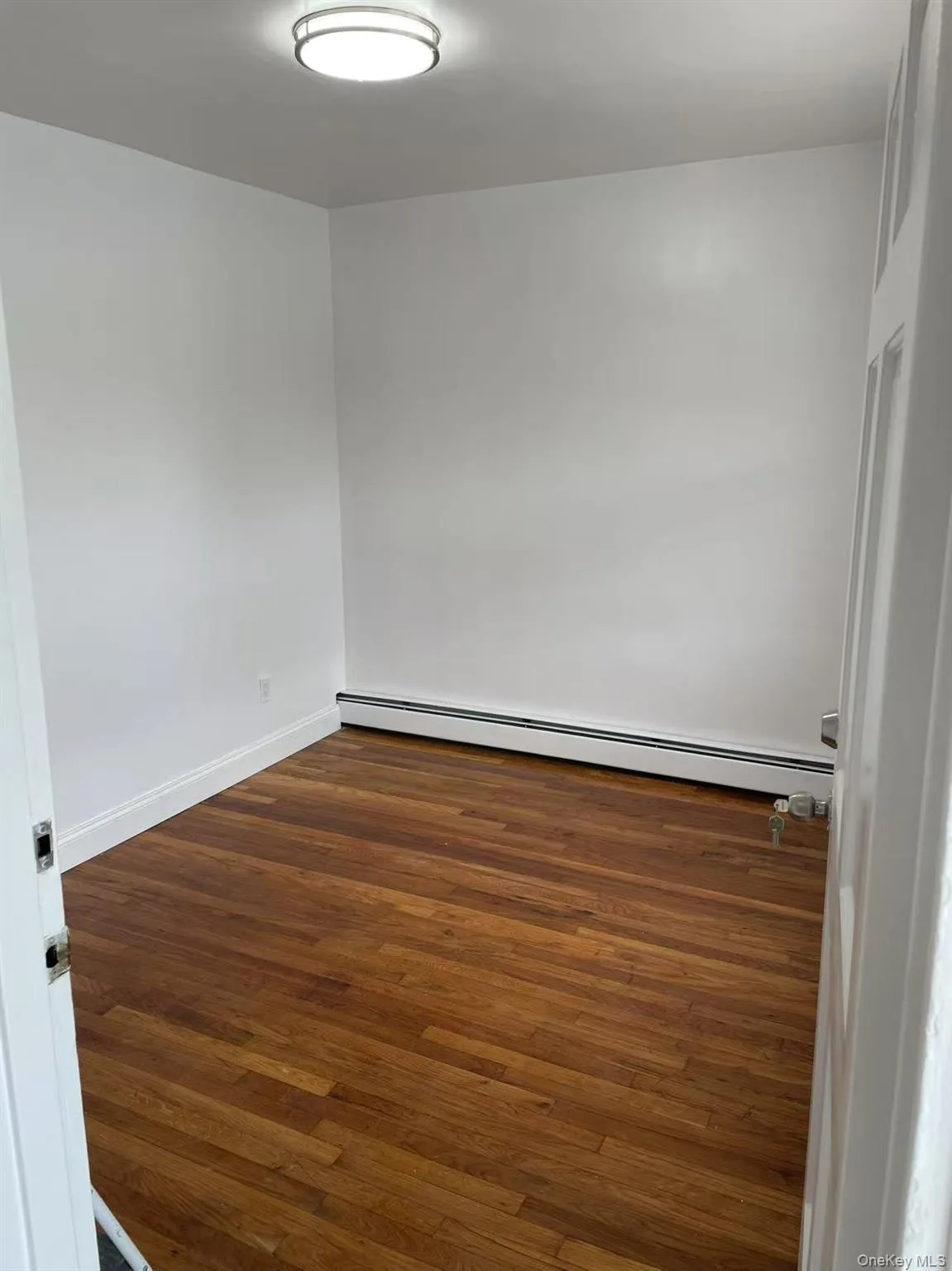 Spare room featuring dark wood-style floors and a baseboard heating unit Spare room featuring dark wood-style floors and a baseboard heating unit