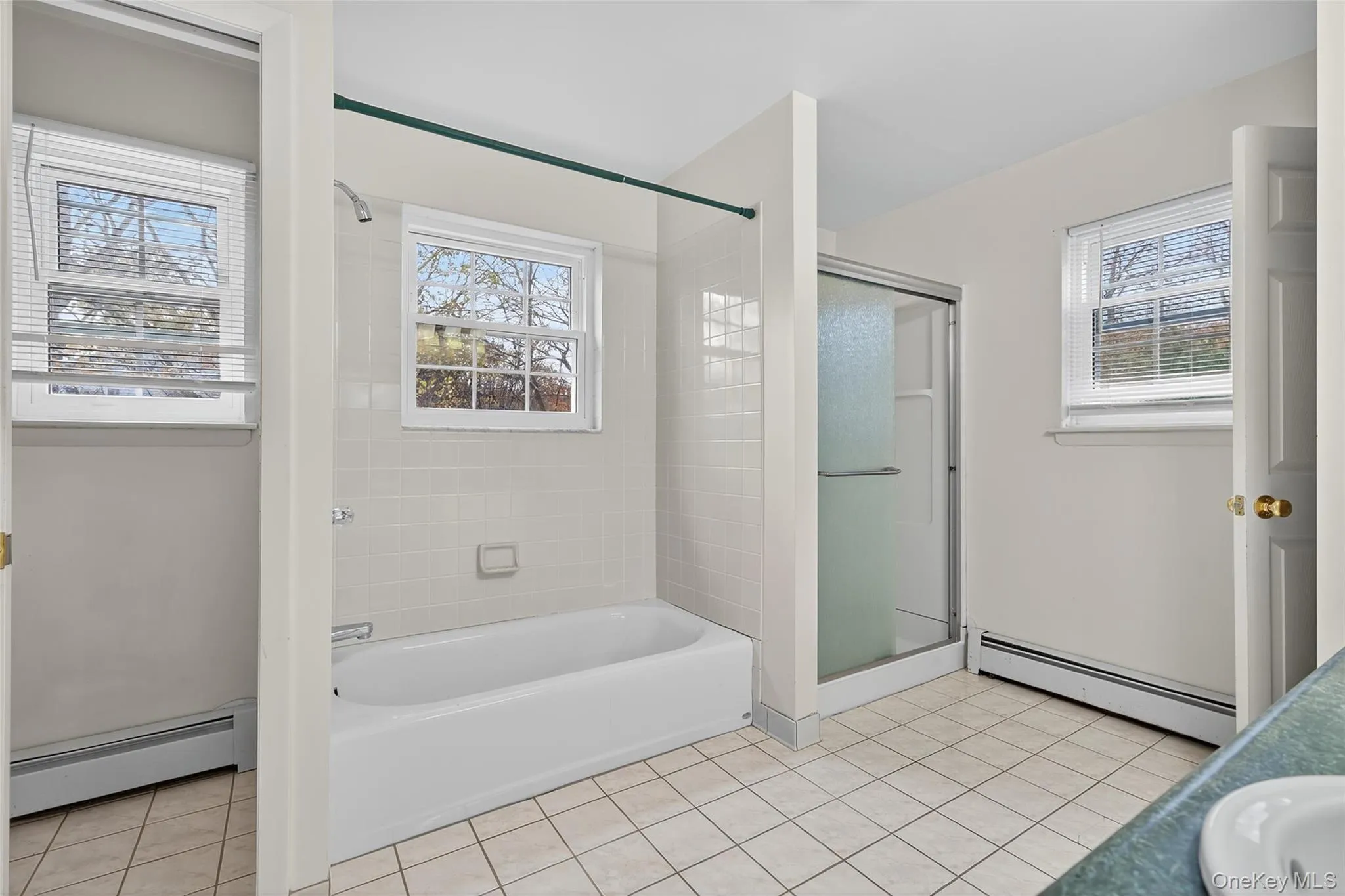 Bathroom with a baseboard heating unit, light tile patterned floors, and vanity Bathroom with a baseboard heating unit, light tile patterned floors, and vanity