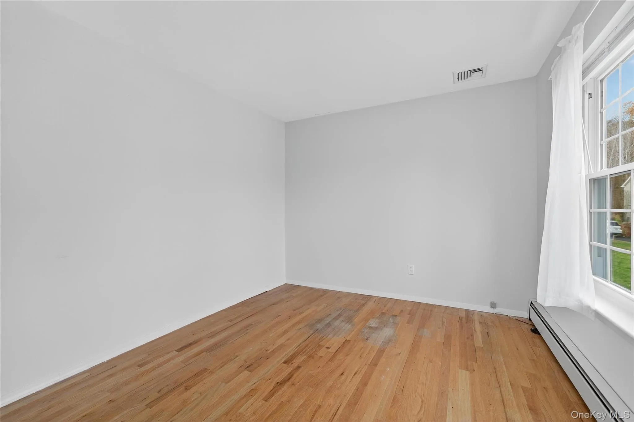 Spare room with a baseboard heating unit and light wood-style floors Spare room with a baseboard heating unit and light wood-style floors