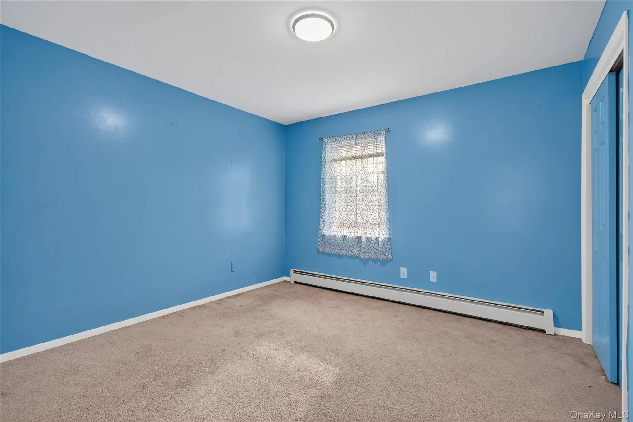Carpeted spare room featuring a baseboard heating unit and baseboards Carpeted spare room featuring a baseboard heating unit and baseboards
