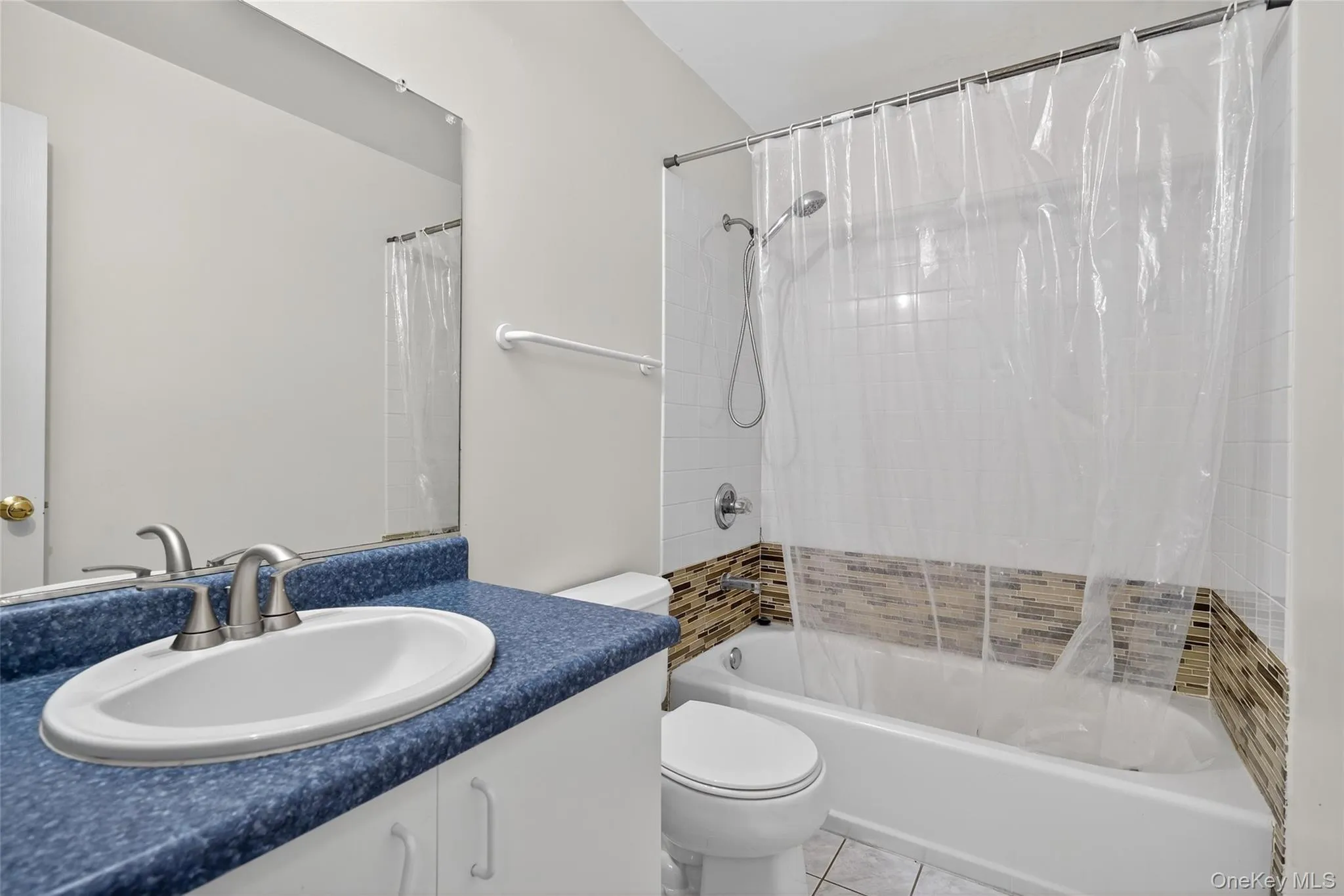 Full bathroom with shower / bathtub combination with curtain, vanity, and light tile patterned floors Full bathroom with shower / bathtub combination with curtain, vanity, and light tile patterned floors