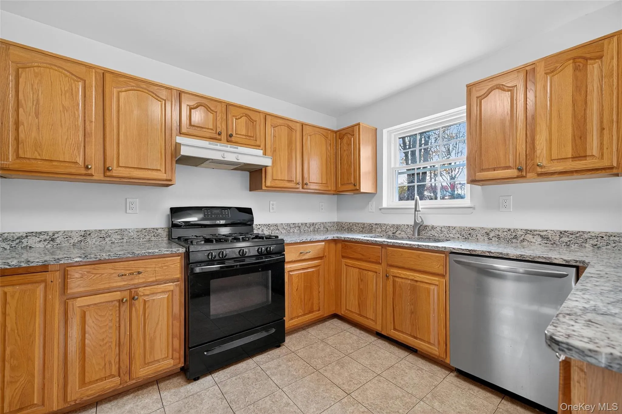 Kitchen featuring black gas range, dishwasher, and light stone countertops Kitchen featuring black gas range, dishwasher, and light stone countertops