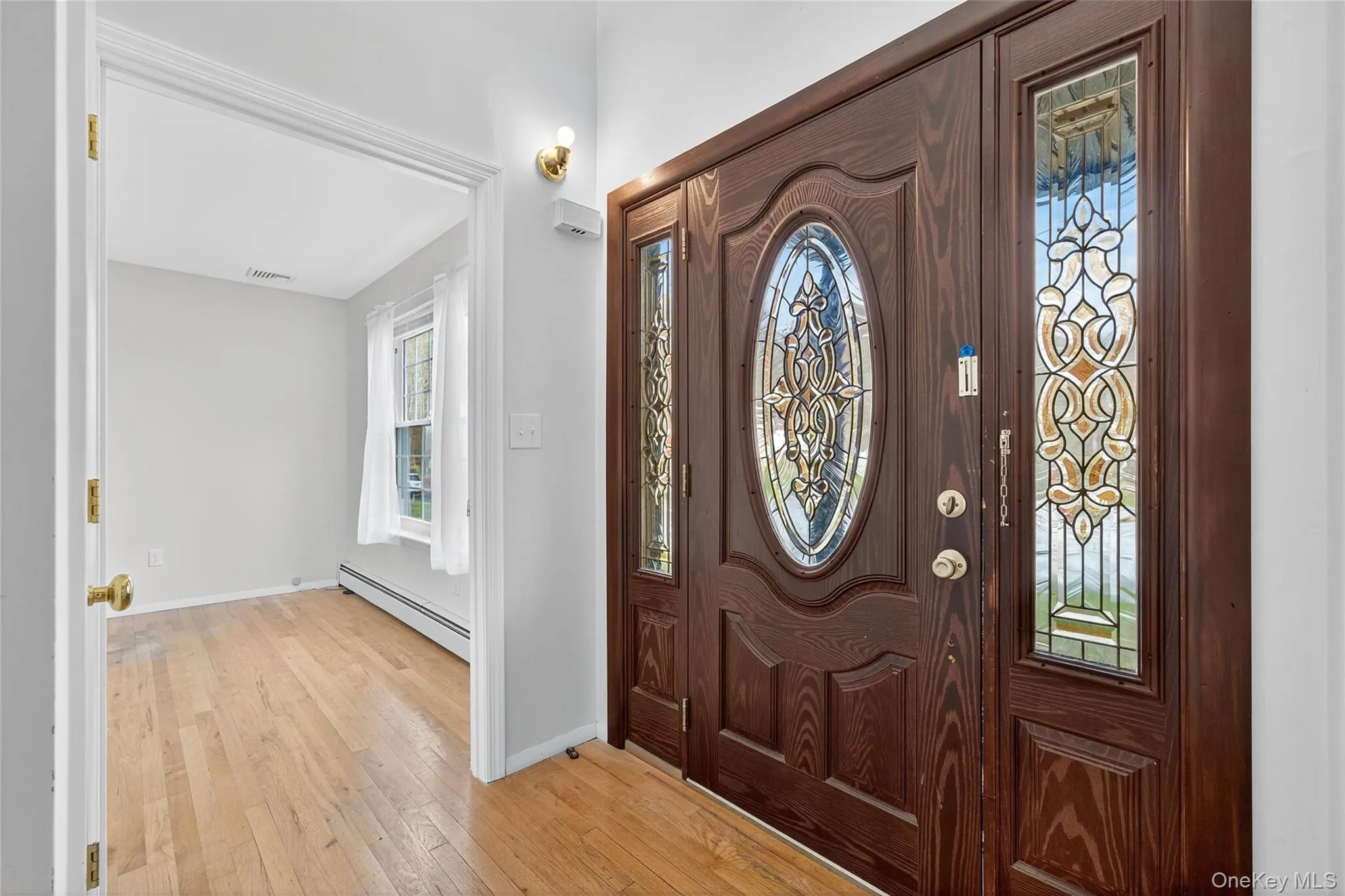 Foyer entrance featuring light wood-type flooring and a baseboard heating unit Foyer entrance featuring light wood-type flooring and a baseboard heating unit