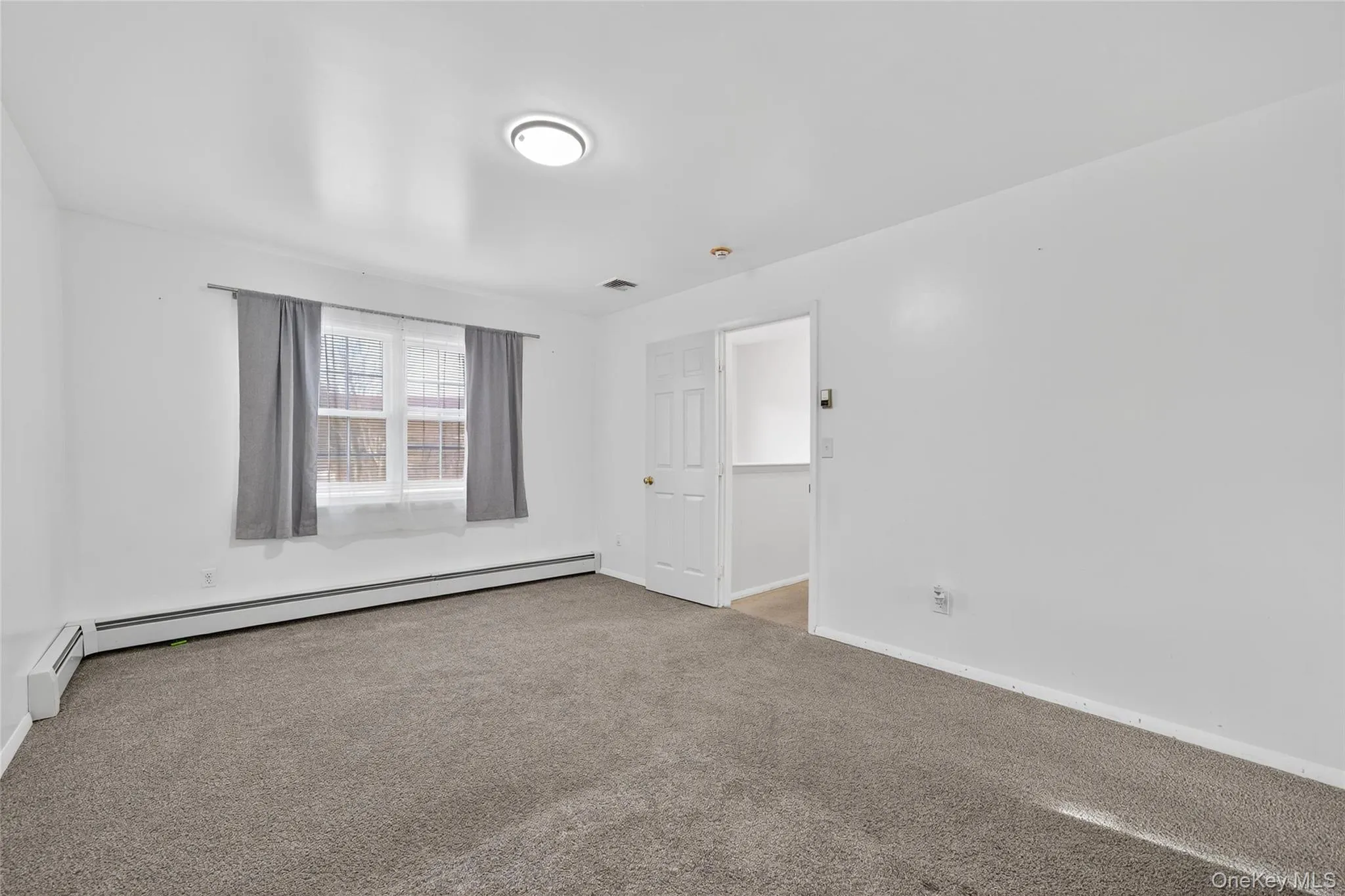 Unfurnished room with carpet and a baseboard radiator Unfurnished room with carpet and a baseboard radiator