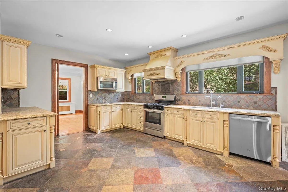 Kitchen featuring backsplash, stainless steel appliances, cream cabinetry, recessed lighting, and custom exhaust hood Kitchen featuring backsplash, stainless steel appliances, cream cabinetry, recessed lighting, and custom exhaust hood