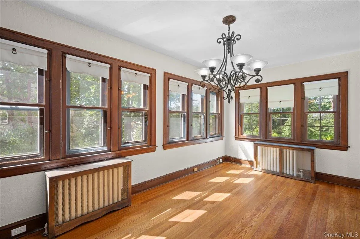 Unfurnished family room featuring radiator and a chandelier Unfurnished family room featuring radiator and a chandelier