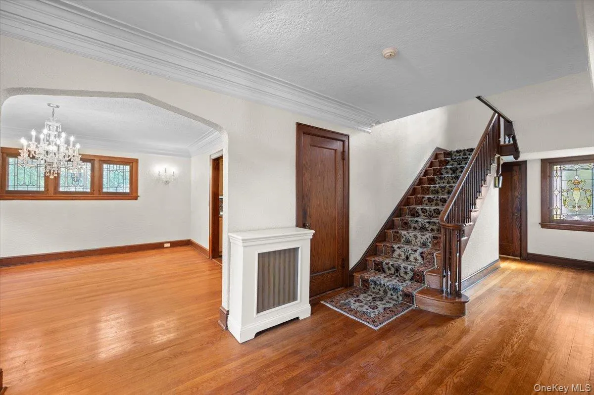 Stairs featuring healthy amount of natural light, a textured ceiling, wood finished floors, ornamental molding, and arched walkways Stairs featuring healthy amount of natural light, a textured ceiling, wood finished floors, ornamental molding, and arched walkways