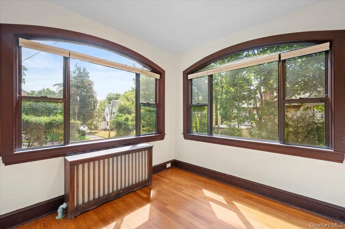 Empty room with radiator heating unit and light wood-style floors Empty room with radiator heating unit and light wood-style floors