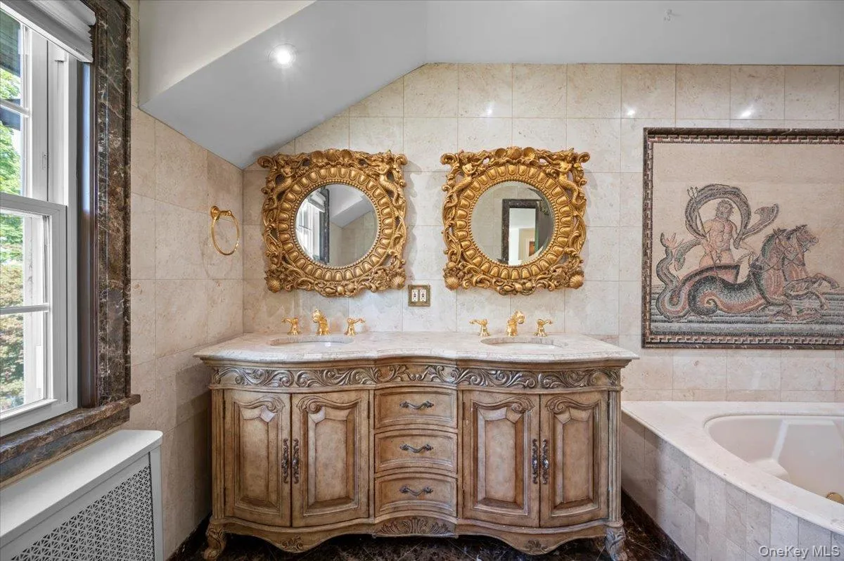 Bathroom featuring tile walls, radiator heating unit, double vanity, a bath, and lofted ceiling Bathroom featuring tile walls, radiator heating unit, double vanity, a bath, and lofted ceiling