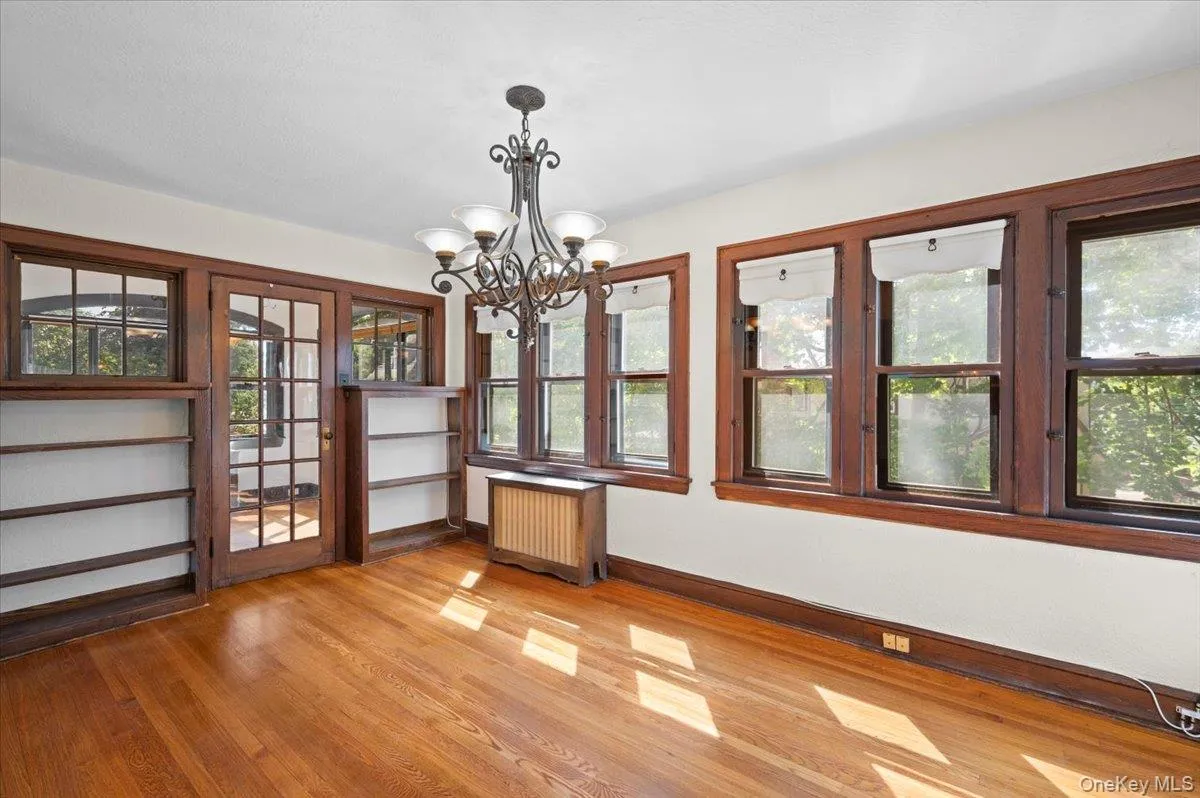 Unfurnished sunroom with radiator, a chandelier, and wood finished floors Unfurnished sunroom with radiator, a chandelier, and wood finished floors