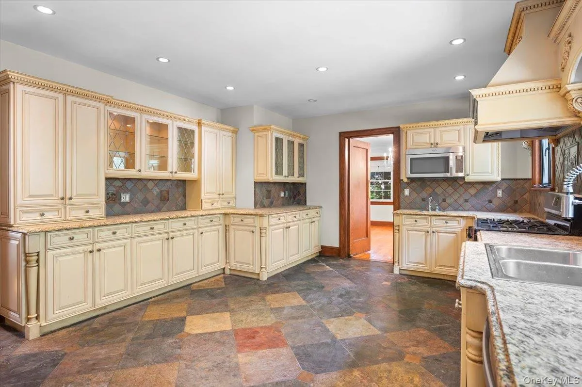 Kitchen featuring glass insert cabinets, cream cabinetry, recessed lighting, premium range hood, and decorative backsplash Kitchen featuring glass insert cabinets, cream cabinetry, recessed lighting, premium range hood, and decorative backsplash