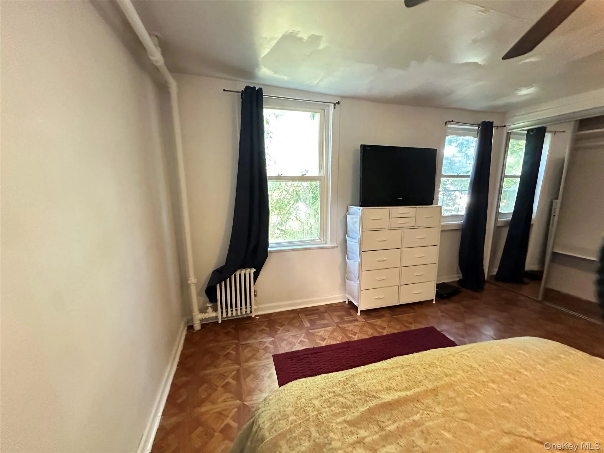 Bedroom with radiator heating unit, a closet, and ceiling fan Bedroom with radiator heating unit, a closet, and ceiling fan