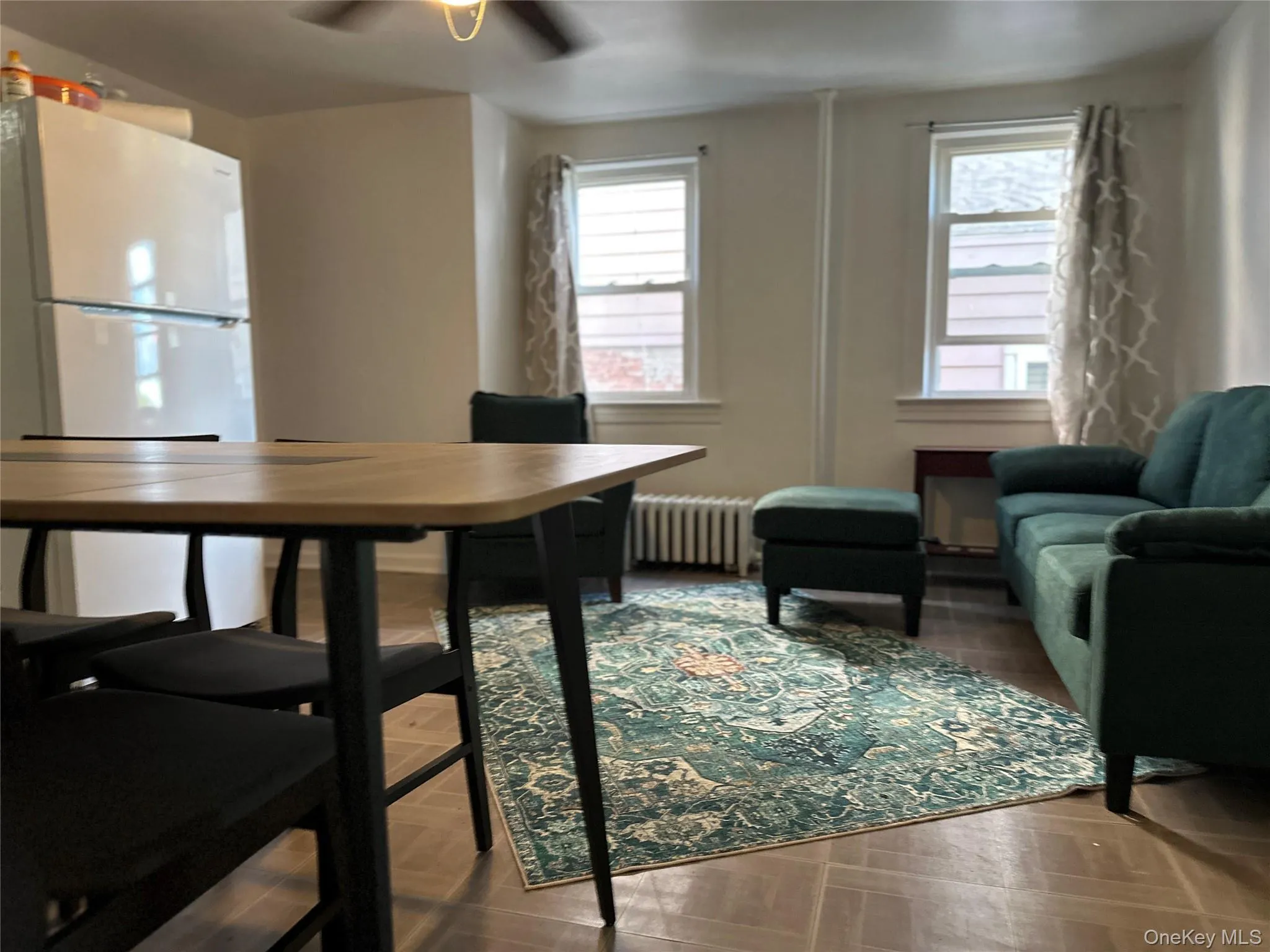Dining room with radiator heating unit, parquet flooring, and a ceiling fan Dining room with radiator heating unit, parquet flooring, and a ceiling fan