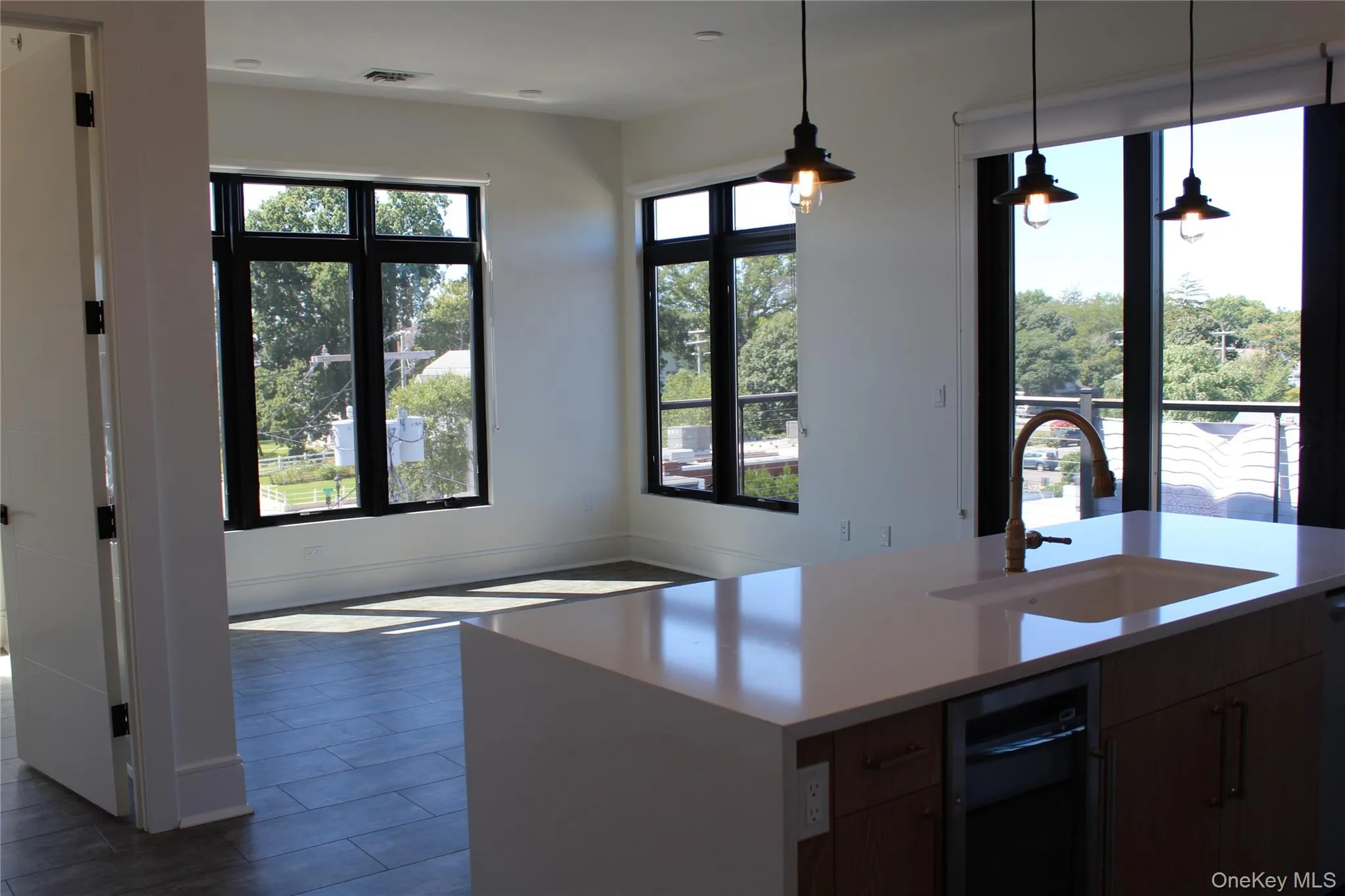 Kitchen featuring pendant lighting, a kitchen island with sink, light stone counters, and dark wood-type flooring Kitchen featuring pendant lighting, a kitchen island with sink, light stone counters, and dark wood-type flooring