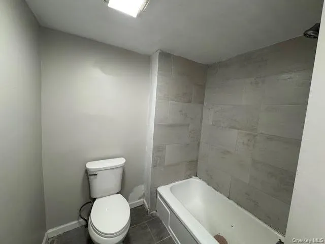 Bathroom with dark tile patterned flooring and shower / bathtub combination Bathroom with dark tile patterned flooring and shower / bathtub combination