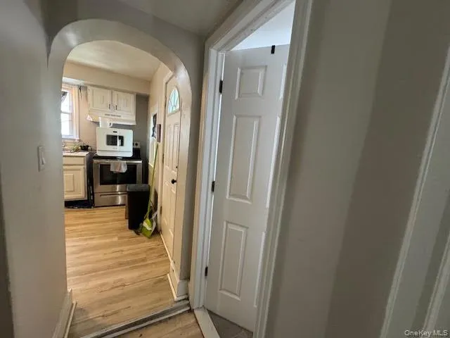 Hall featuring arched walkways and light wood-type flooring Hall featuring arched walkways and light wood-type flooring