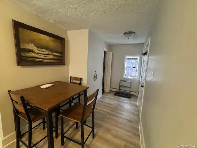 Dining space with a textured ceiling, light wood-style flooring, and a baseboard heating unit Dining space with a textured ceiling, light wood-style flooring, and a baseboard heating unit