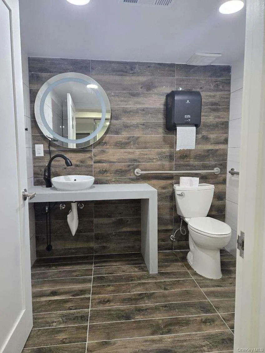 Half bath featuring toilet and tile walls Half bath featuring toilet and tile walls
