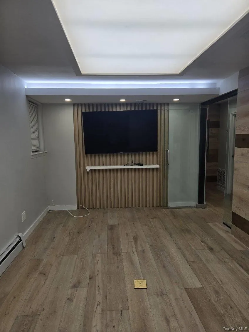 Unfurnished living room featuring baseboard heating, light wood-style floors, and recessed lighting Unfurnished living room featuring baseboard heating, light wood-style floors, and recessed lighting