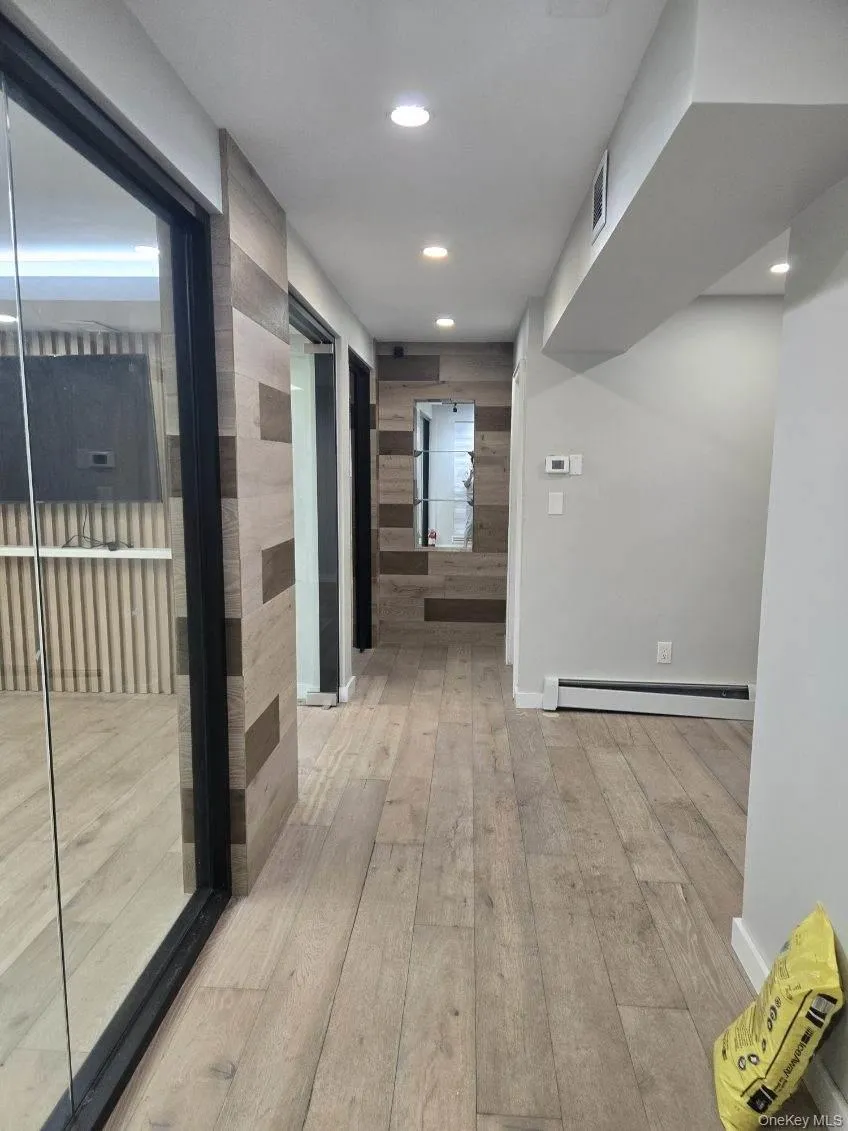 Corridor with light wood finished floors, a baseboard radiator, and recessed lighting Corridor with light wood finished floors, a baseboard radiator, and recessed lighting