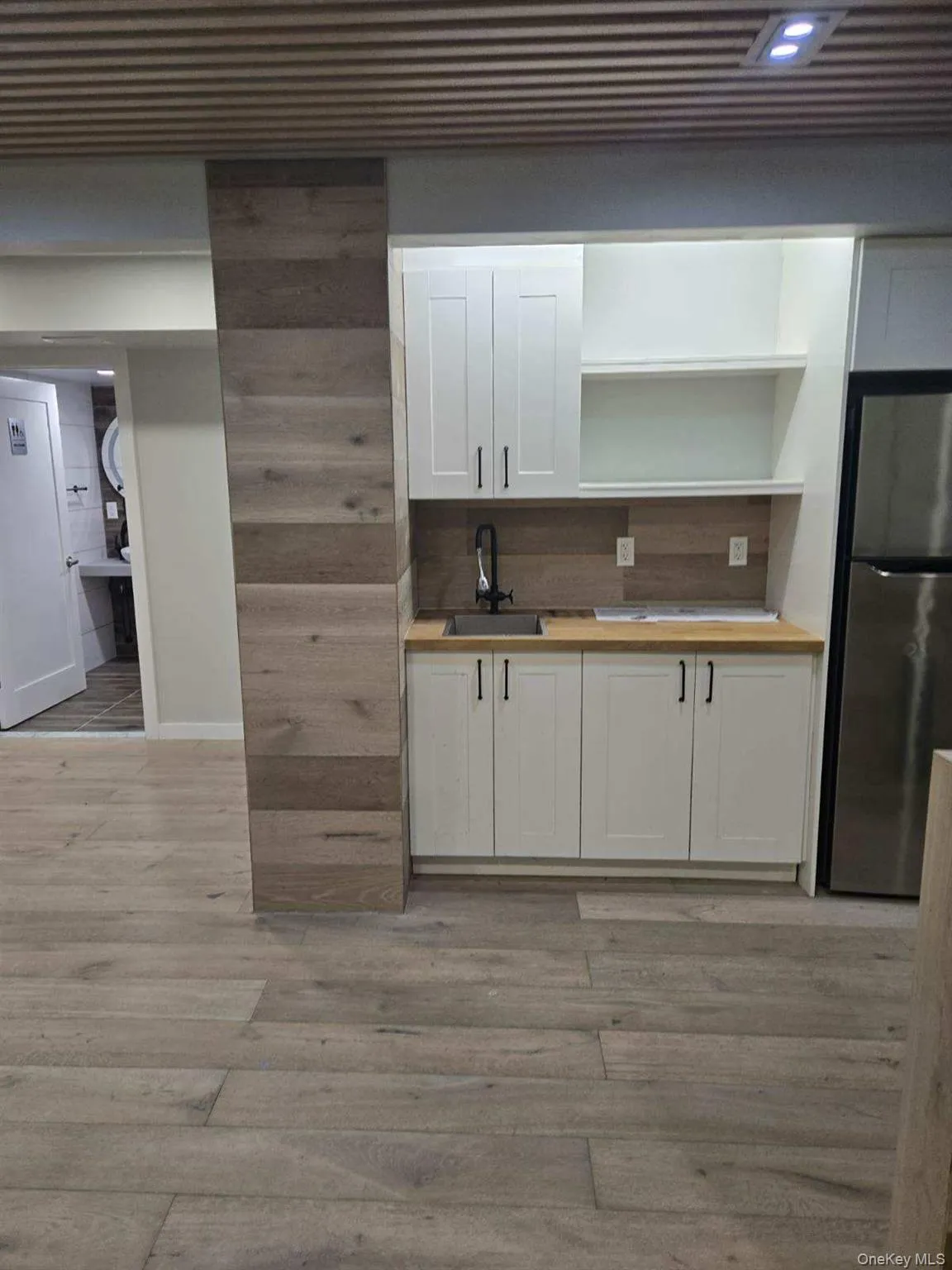 Kitchen with white cabinets, freestanding refrigerator, light wood-style floors, and open shelves Kitchen with white cabinets, freestanding refrigerator, light wood-style floors, and open shelves