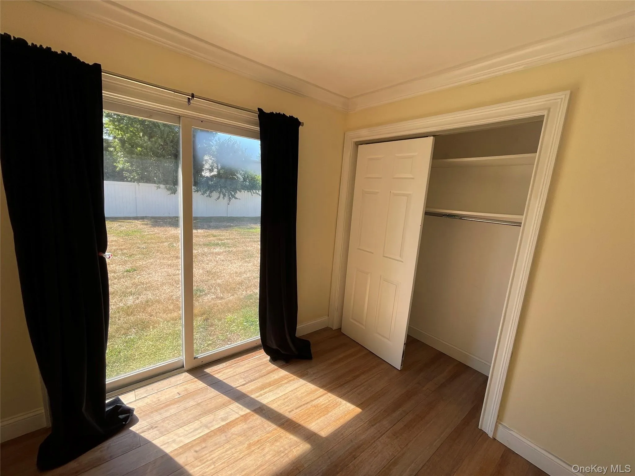 Unfurnished bedroom featuring crown molding, wood finished floors, and a closet Unfurnished bedroom featuring crown molding, wood finished floors, and a closet