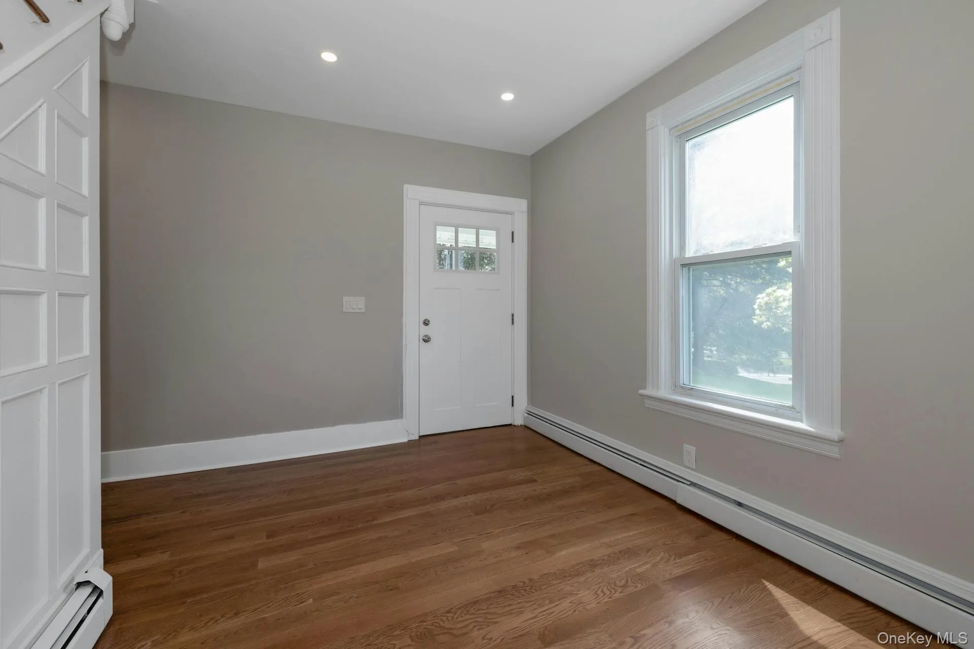 Foyer entrance with a baseboard radiator, dark wood-style floors, and recessed lighting Foyer entrance with a baseboard radiator, dark wood-style floors, and recessed lighting
