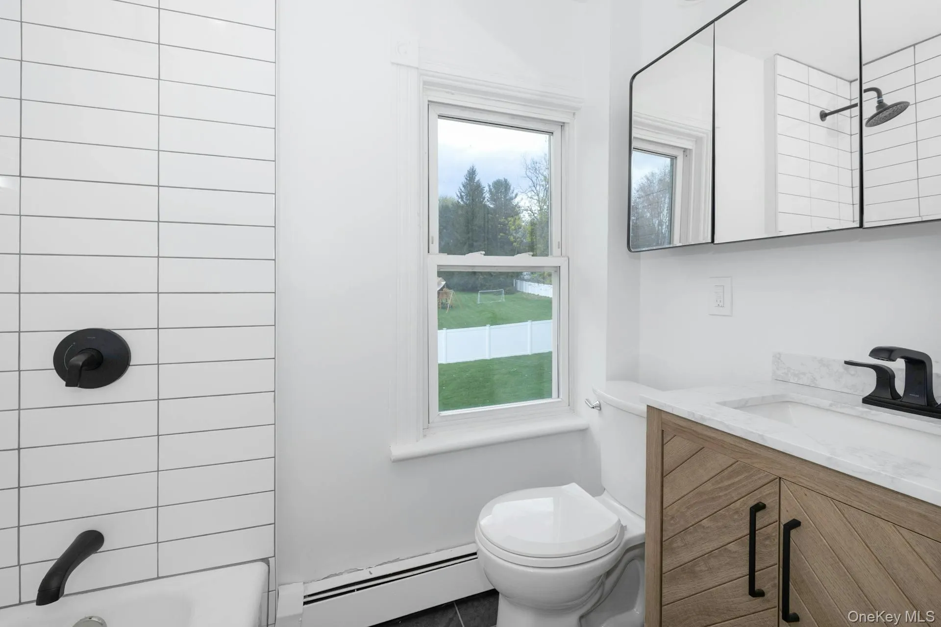 Bathroom featuring vanity, baseboard heating, and washtub / shower combination Bathroom featuring vanity, baseboard heating, and washtub / shower combination