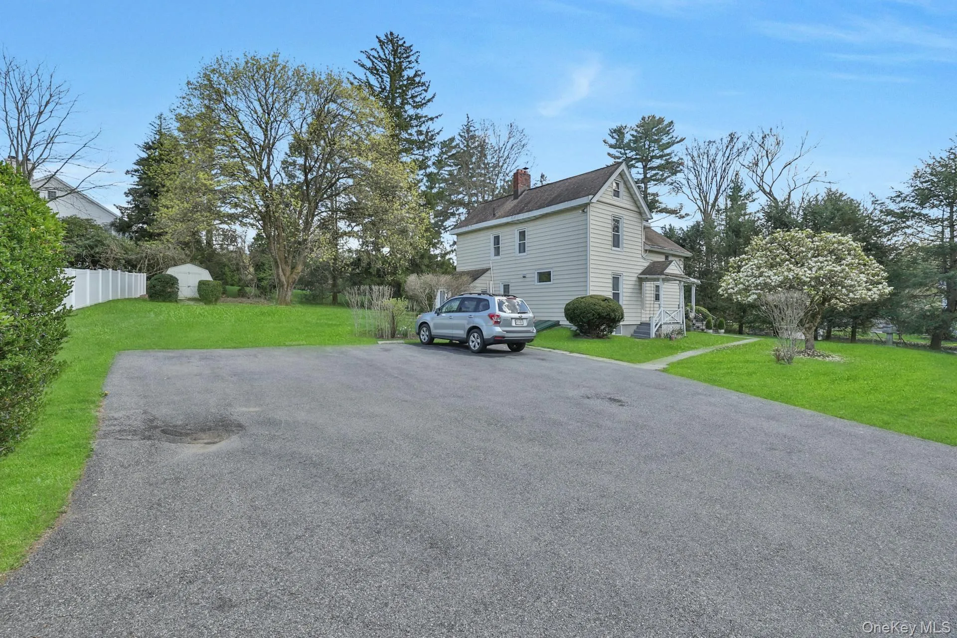 View of side of home featuring a chimney, a storage unit, and driveway View of side of home featuring a chimney, a storage unit, and driveway