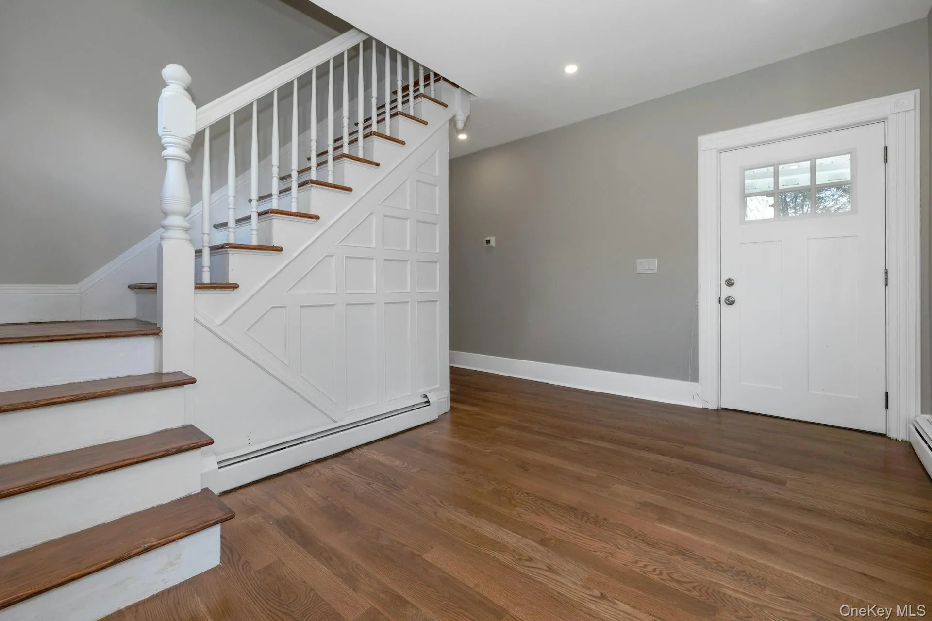 Entrance foyer with a baseboard radiator, dark wood finished floors, stairs, and recessed lighting Entrance foyer with a baseboard radiator, dark wood finished floors, stairs, and recessed lighting