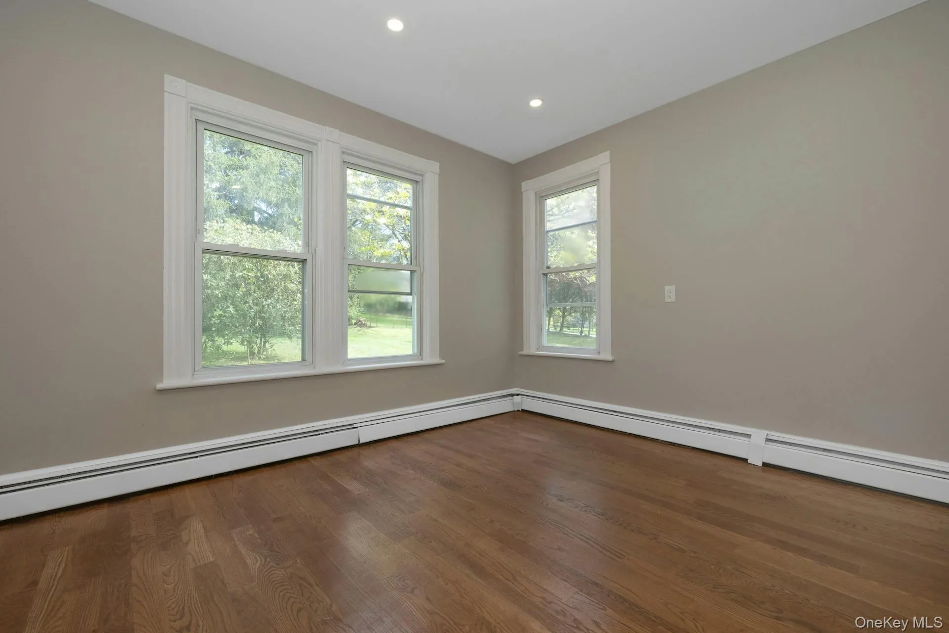 Empty room with dark wood finished floors, recessed lighting, and baseboard heating Empty room with dark wood finished floors, recessed lighting, and baseboard heating
