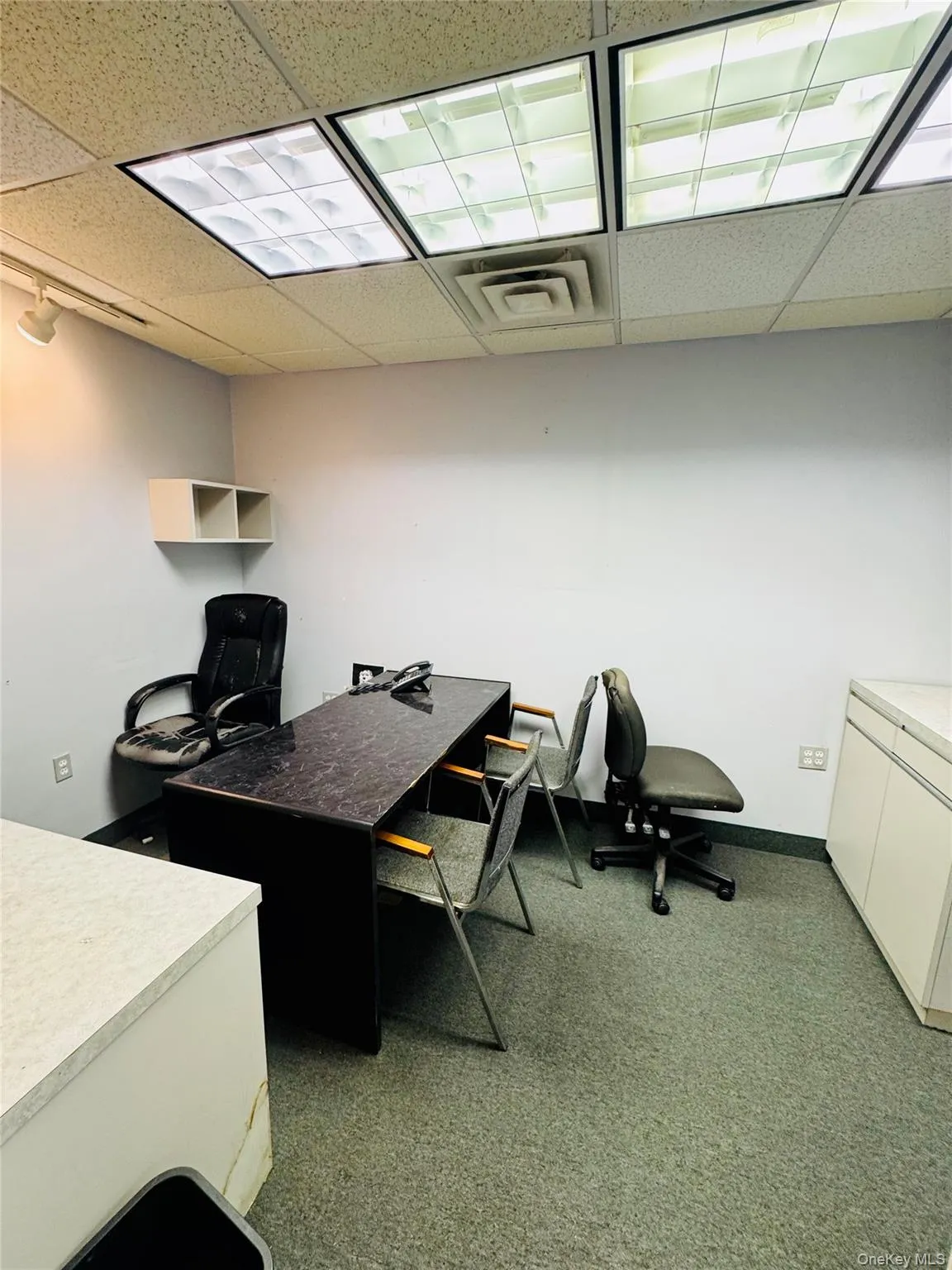 Office space with a drop ceiling and dark carpet Office space with a drop ceiling and dark carpet
