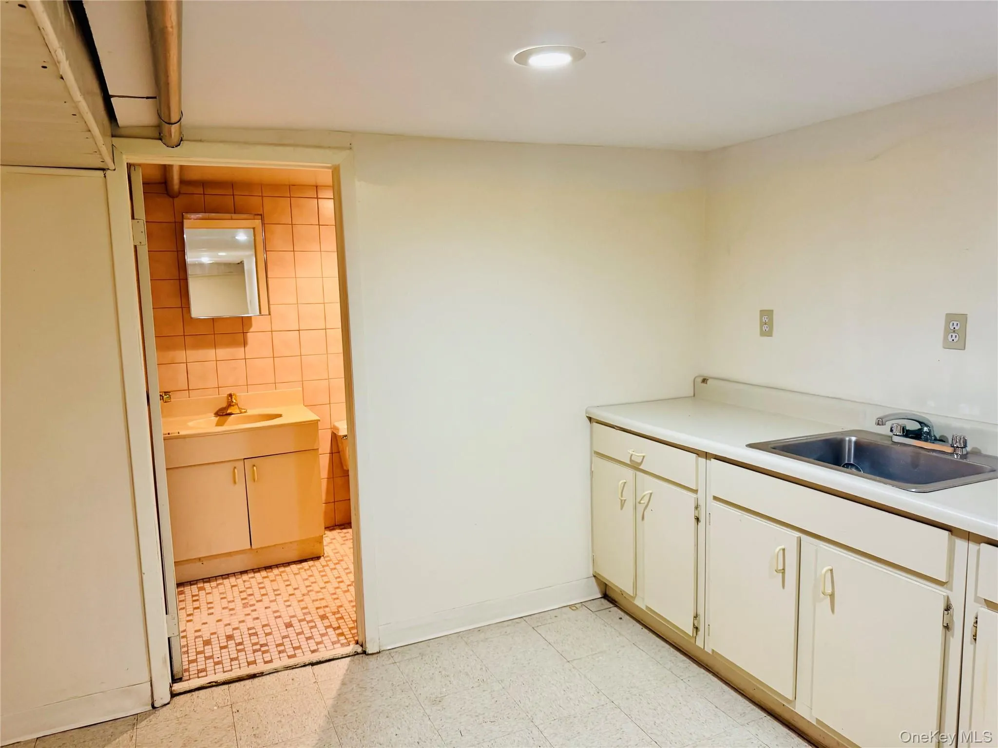 Kitchen with light countertops, light flooring, tile walls, recessed lighting, and white cabinetry Kitchen with light countertops, light flooring, tile walls, recessed lighting, and white cabinetry