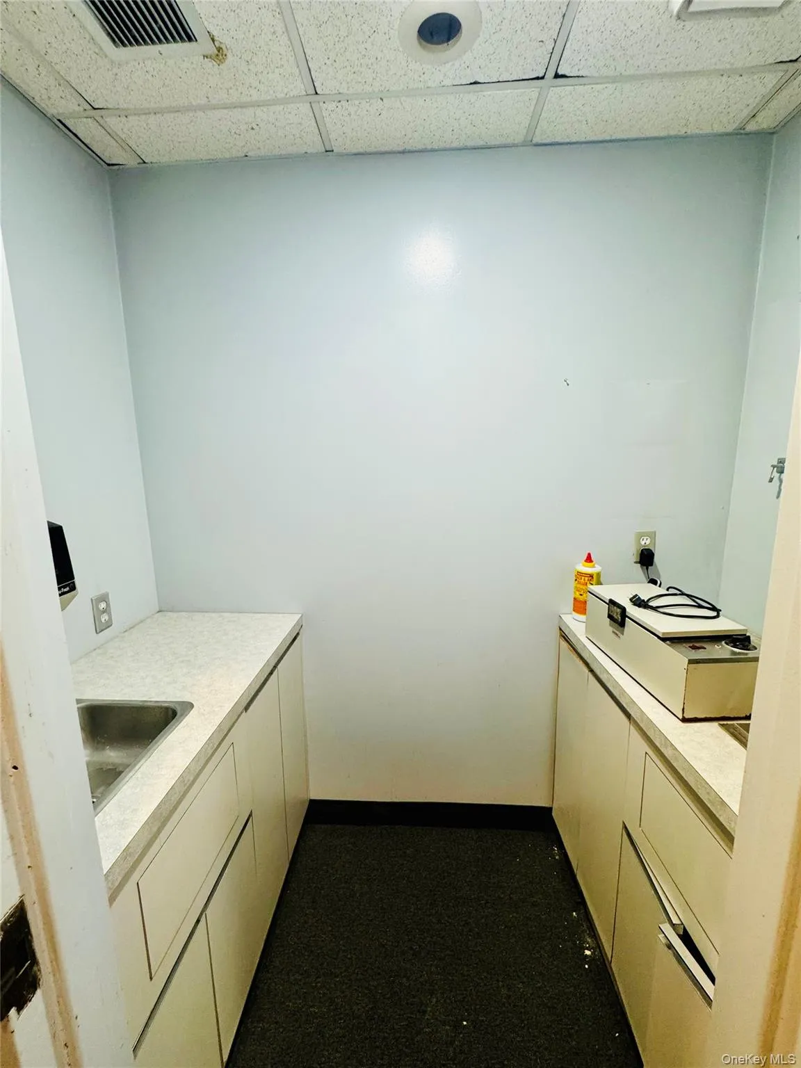 Kitchen with light countertops, a paneled ceiling, and white cabinets Kitchen with light countertops, a paneled ceiling, and white cabinets
