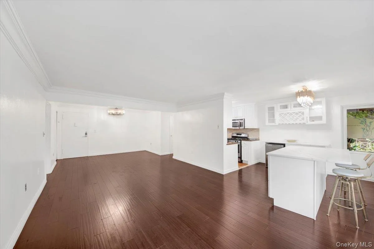 Unfurnished living room featuring a chandelier, dark wood finished floors, and crown molding Unfurnished living room featuring a chandelier, dark wood finished floors, and crown molding