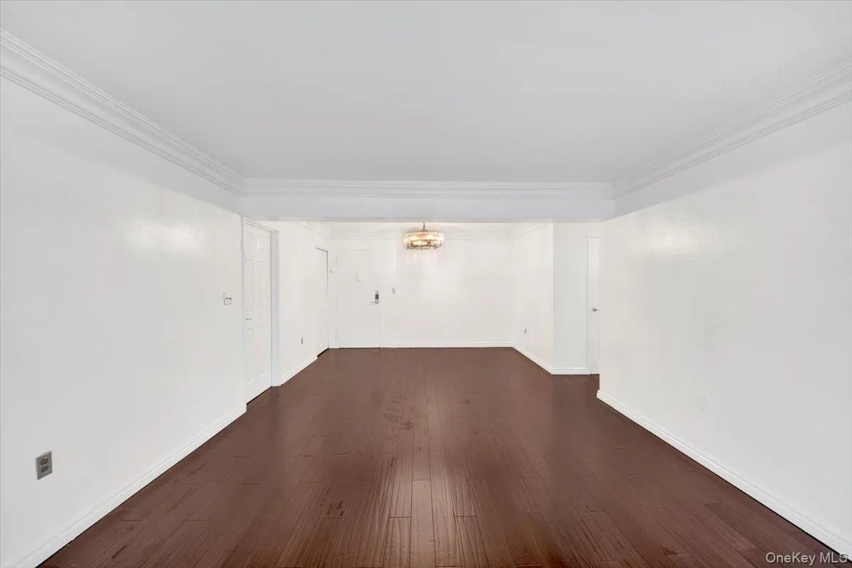 Spare room featuring dark wood finished floors, a chandelier, and ornamental molding Spare room featuring dark wood finished floors, a chandelier, and ornamental molding