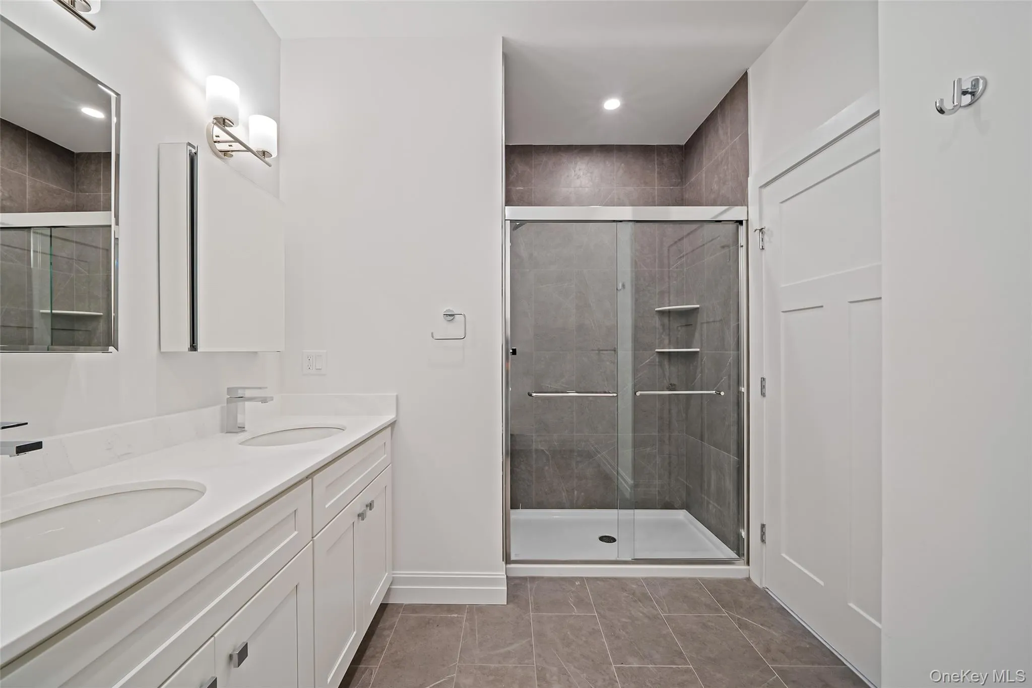 Full bathroom featuring a shower stall, double vanity, light tile patterned floors, and recessed lighting Full bathroom featuring a shower stall, double vanity, light tile patterned floors, and recessed lighting