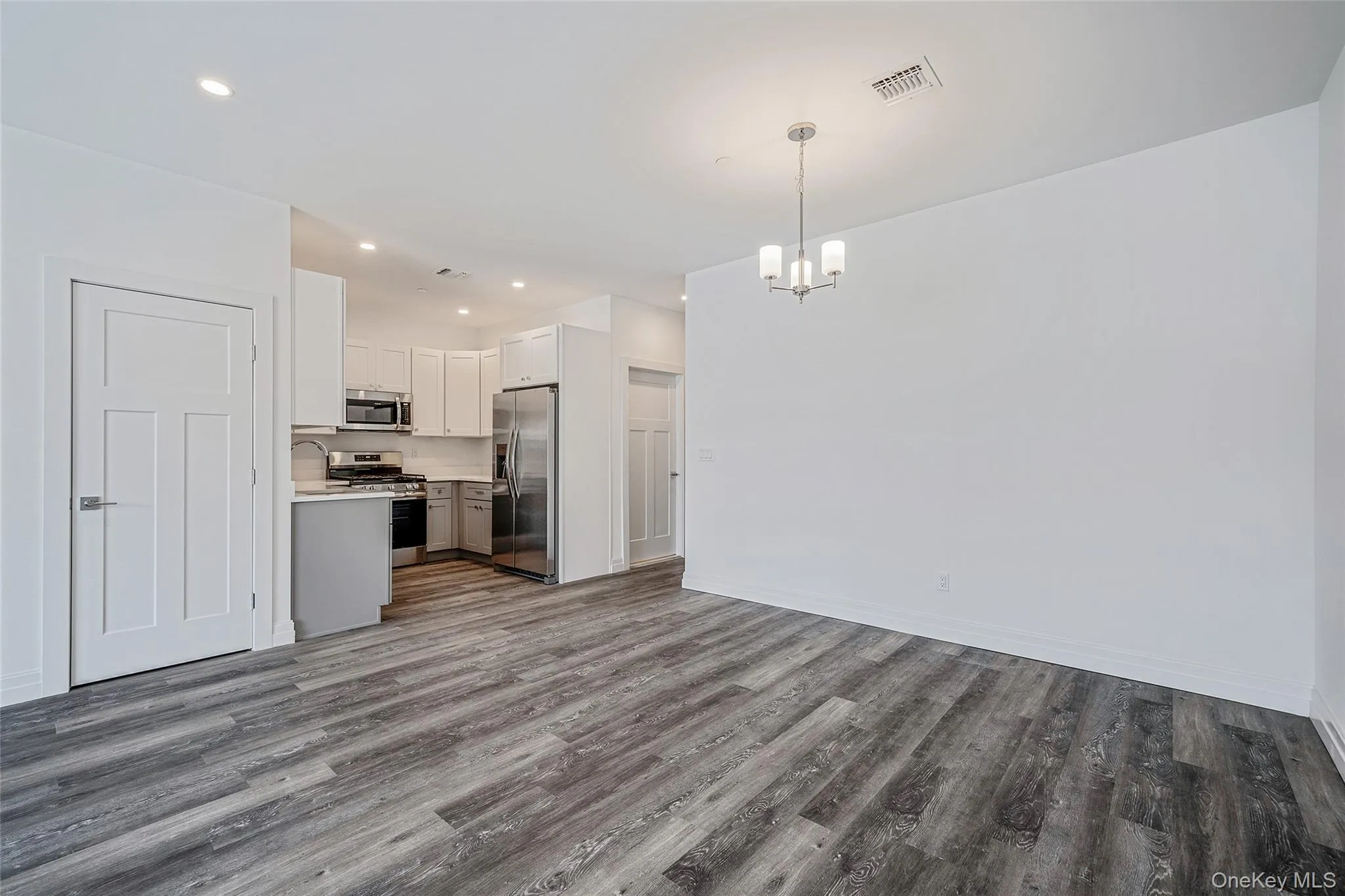 Kitchen with pendant lighting, light countertops, dark wood-type flooring, appliances with stainless steel finishes, and recessed lighting Kitchen with pendant lighting, light countertops, dark wood-type flooring, appliances with stainless steel finishes, and recessed lighting