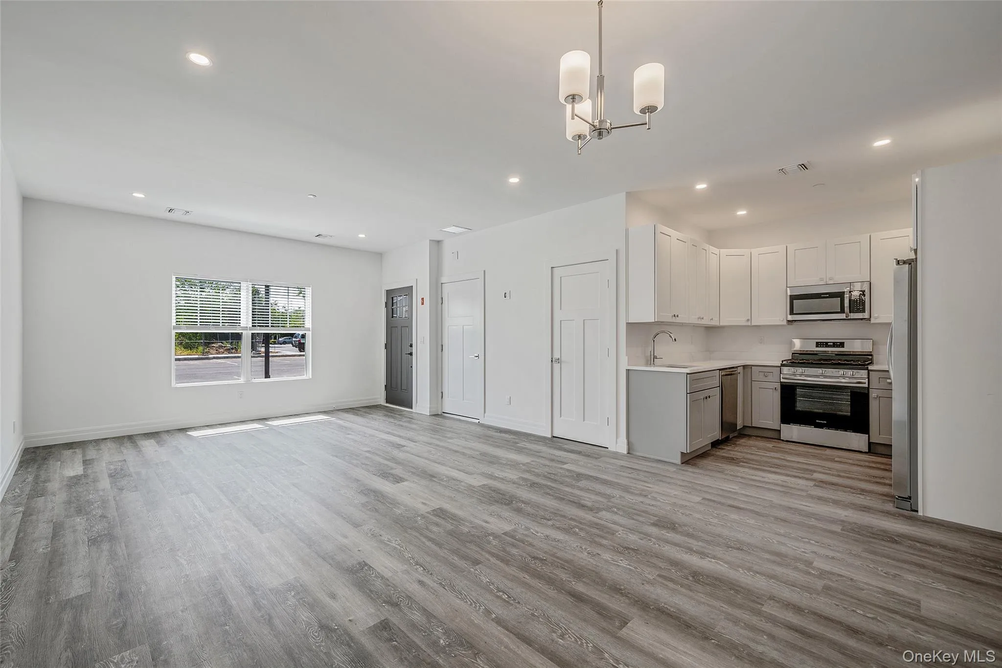 Kitchen featuring open floor plan, appliances with stainless steel finishes, pendant lighting, recessed lighting, and light wood finished floors Kitchen featuring open floor plan, appliances with stainless steel finishes, pendant lighting, recessed lighting, and light wood finished floors