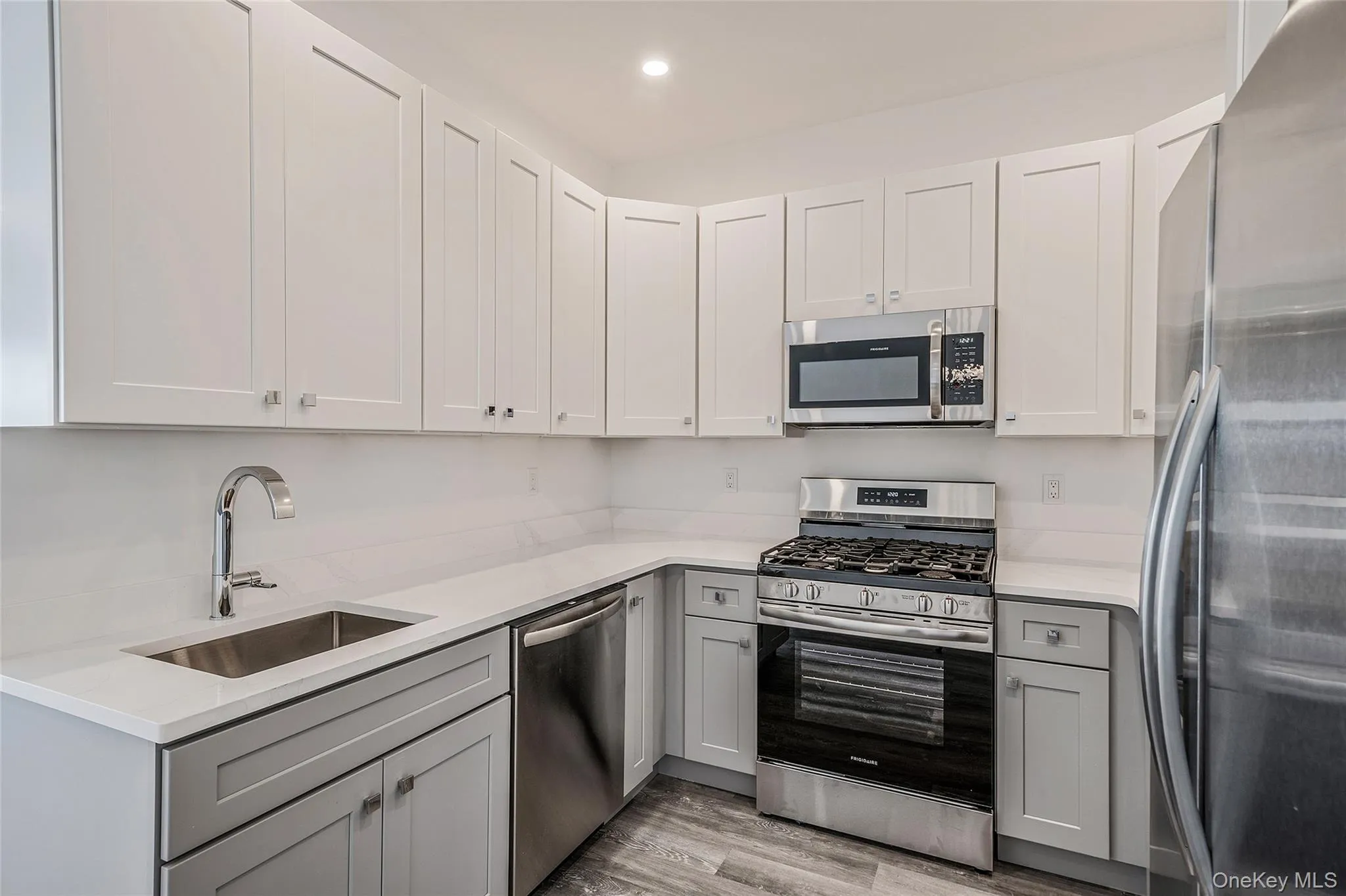 Kitchen with stainless steel appliances, gray cabinetry, light wood-style floors, light stone countertops, and recessed lighting Kitchen with stainless steel appliances, gray cabinetry, light wood-style floors, light stone countertops, and recessed lighting