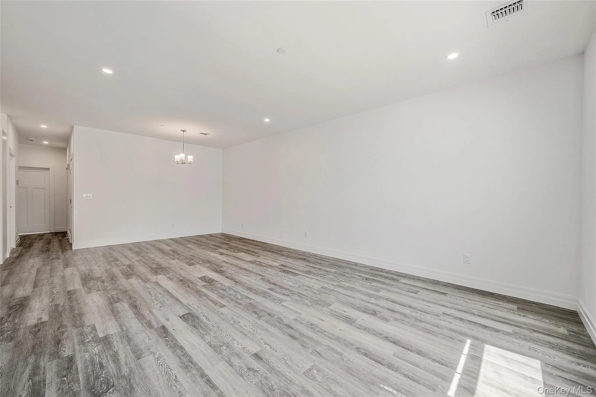 Spare room featuring light wood-style floors, recessed lighting, and a chandelier Spare room featuring light wood-style floors, recessed lighting, and a chandelier