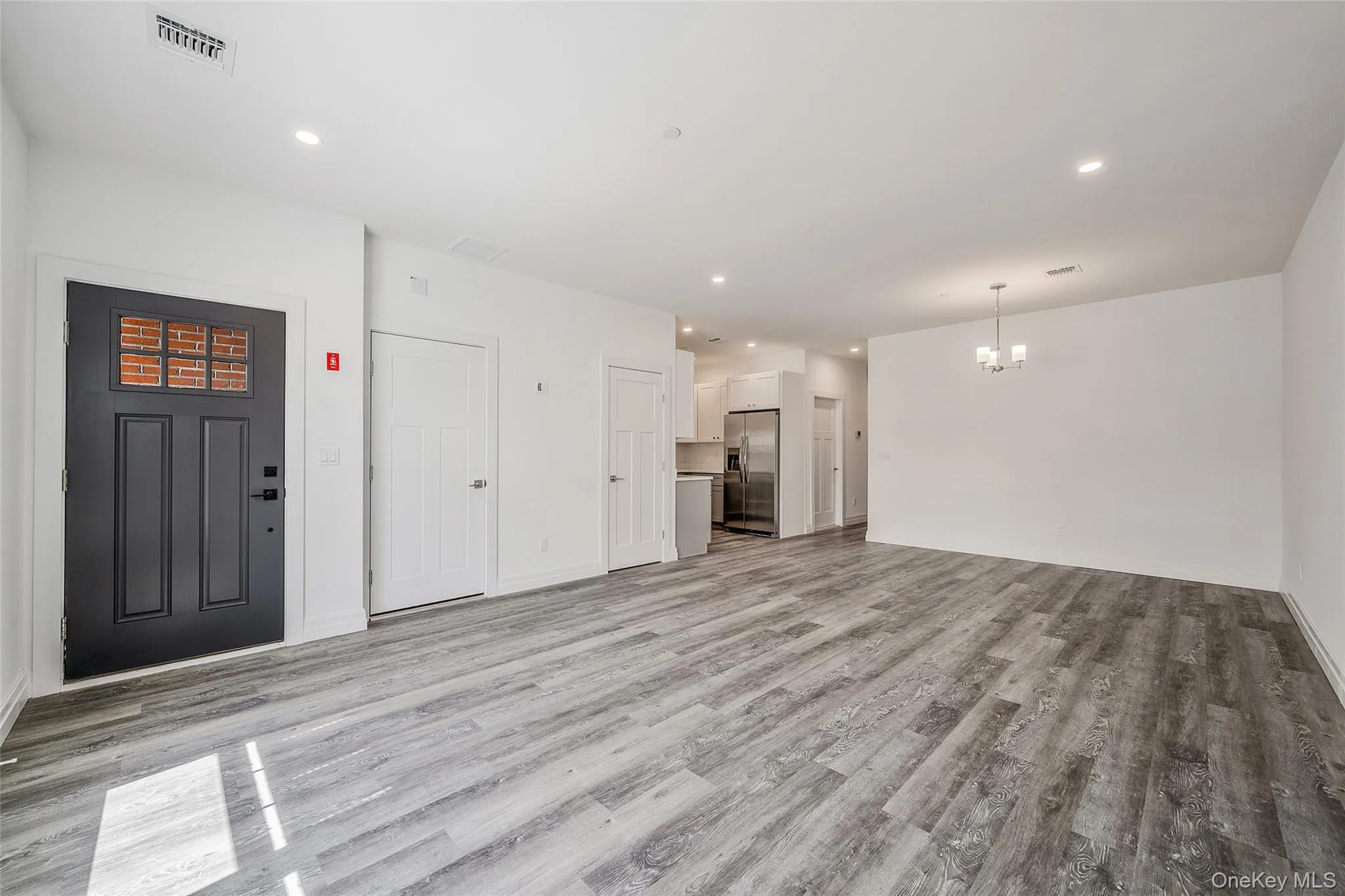 Unfurnished living room with recessed lighting, a chandelier, and light wood-type flooring Unfurnished living room with recessed lighting, a chandelier, and light wood-type flooring