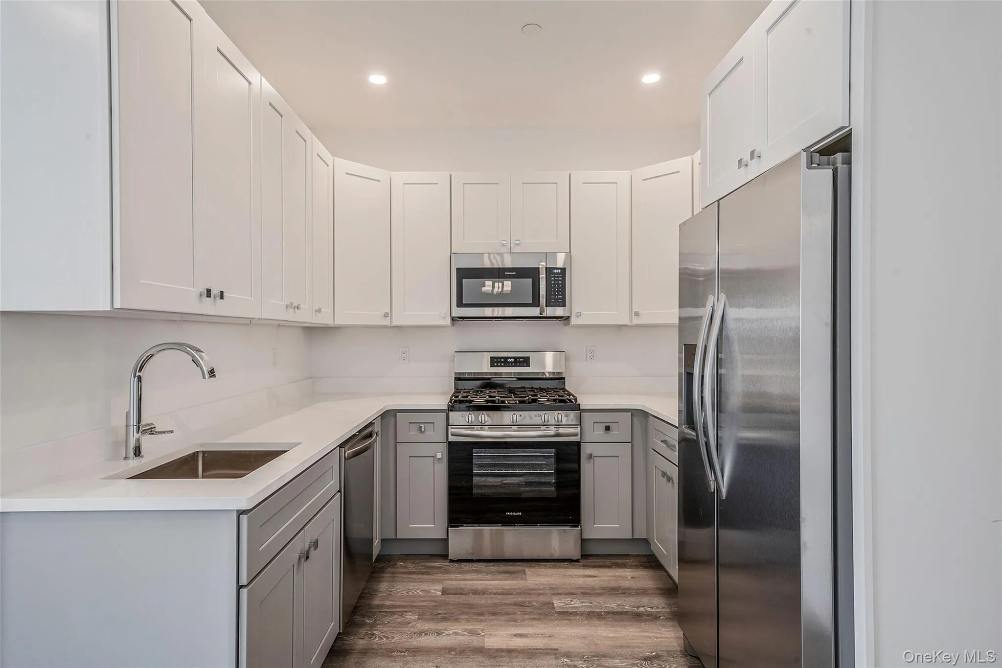 Kitchen with gray cabinets, appliances with stainless steel finishes, light wood finished floors, light stone counters, and white cabinets Kitchen with gray cabinets, appliances with stainless steel finishes, light wood finished floors, light stone counters, and white cabinets
