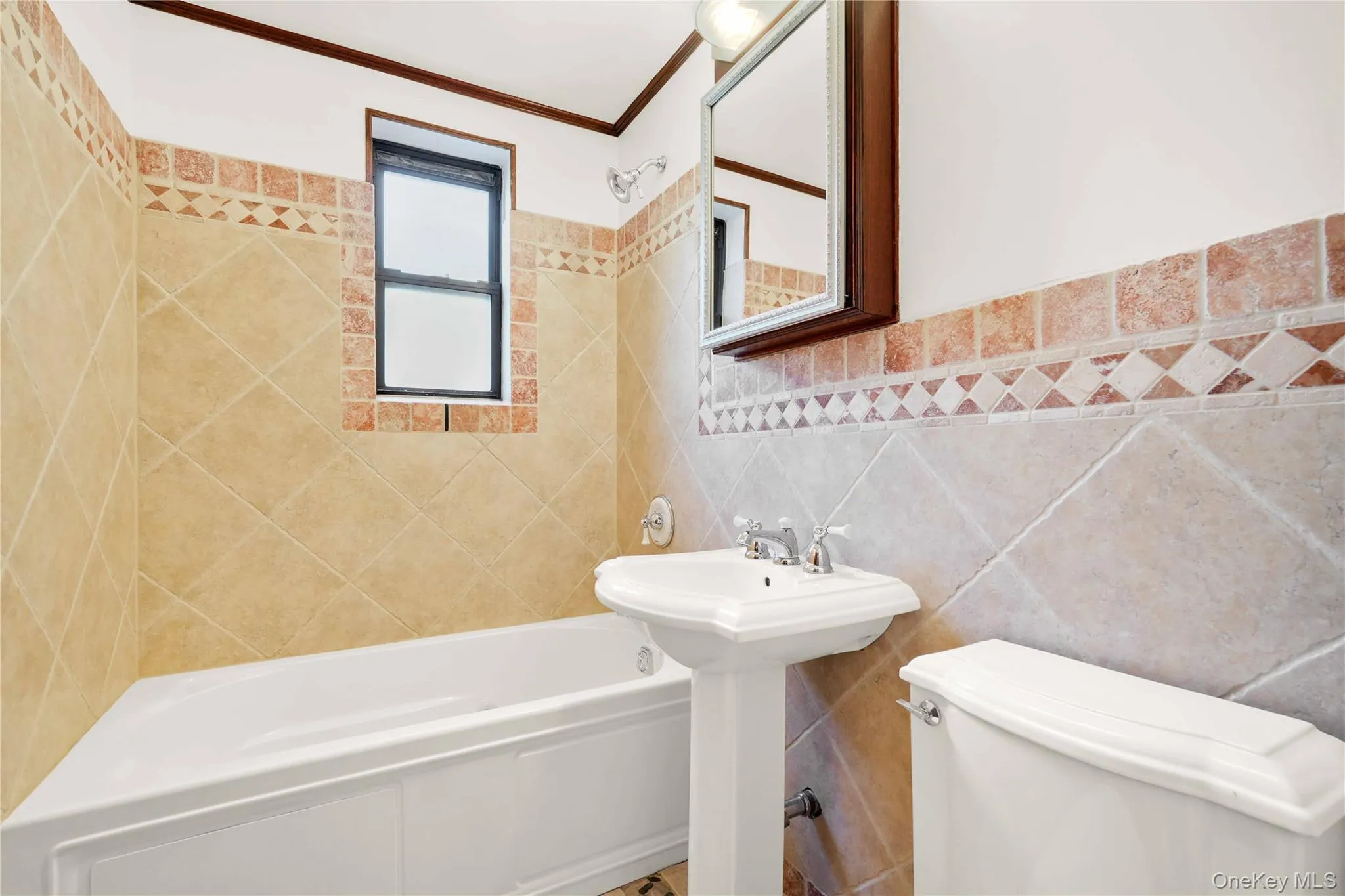 Bathroom with tile walls, shower / washtub combination, a wainscoted wall, and ornamental molding Bathroom with tile walls, shower / washtub combination, a wainscoted wall, and ornamental molding