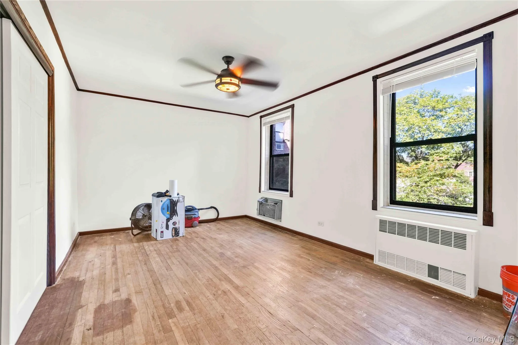 Empty room with crown molding, light wood-style flooring, radiator, and ceiling fan Empty room with crown molding, light wood-style flooring, radiator, and ceiling fan