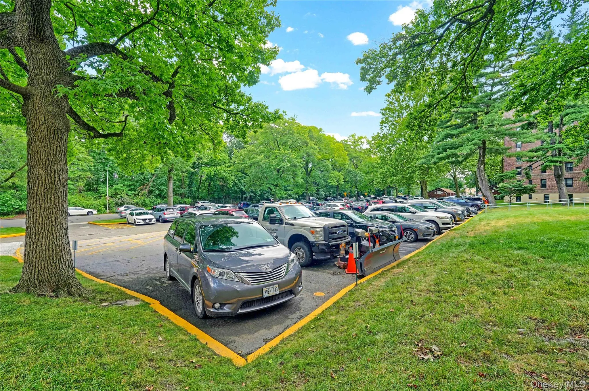 Uncovered parking lot featuring view of wooded area Uncovered parking lot featuring view of wooded area